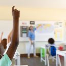 Caucasian female teacher wearing face mask at school, teaching children at school classroom. Education back to school health safety during Covid19 Coronavirus pandemic.