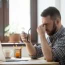 Stressed male massaging nose bridge suffering from headache